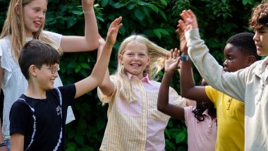 Seks børn uden dørs giver hinanden high fives (modelbillede)