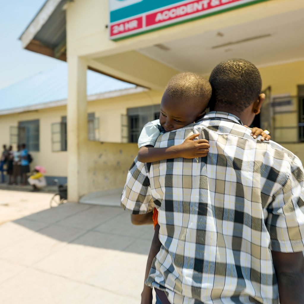 Sygeplejer bærer tre-årig dren til hospitalet i det nordlige Kenya.