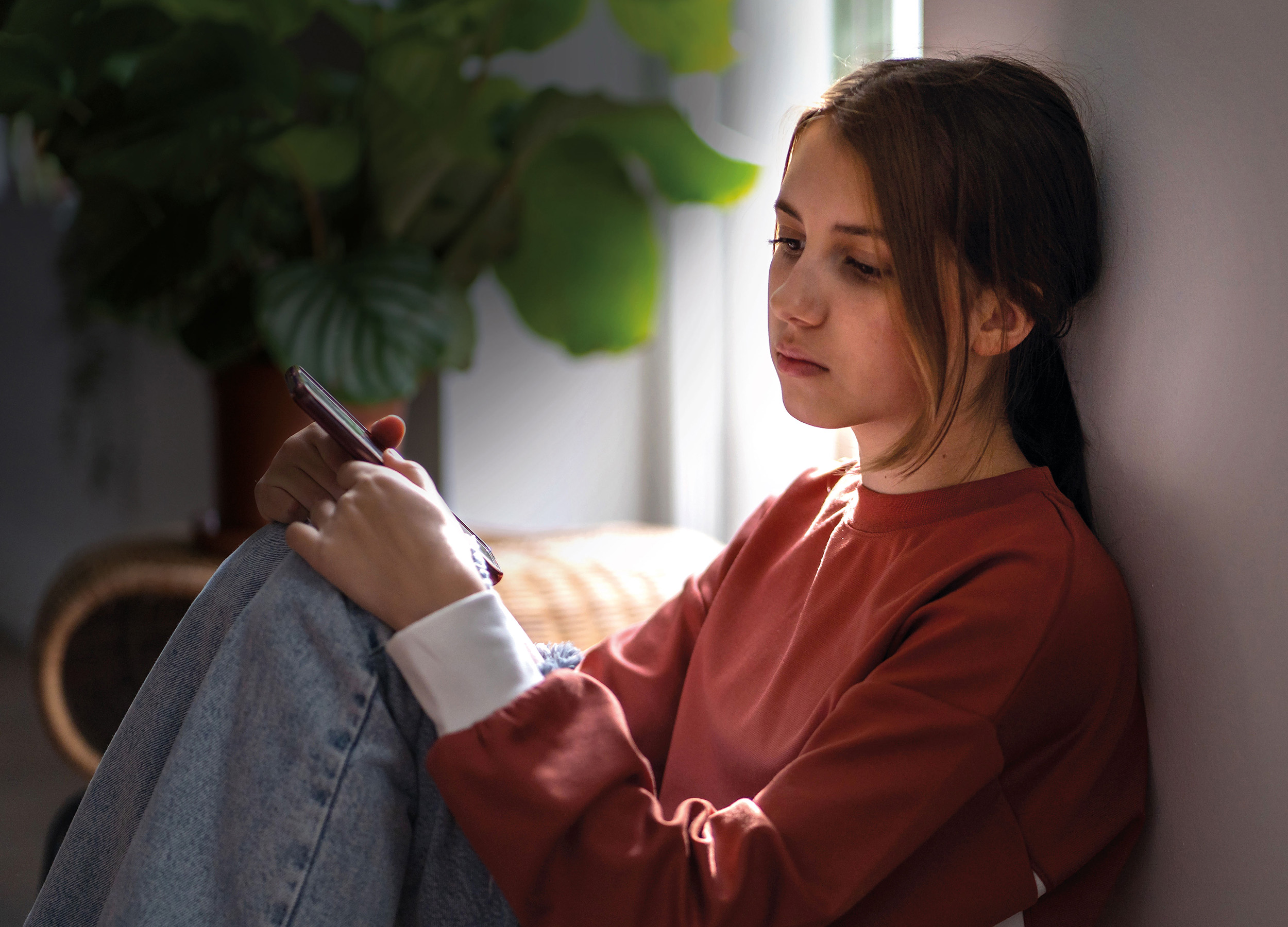 Teenager sidder alene med mobil